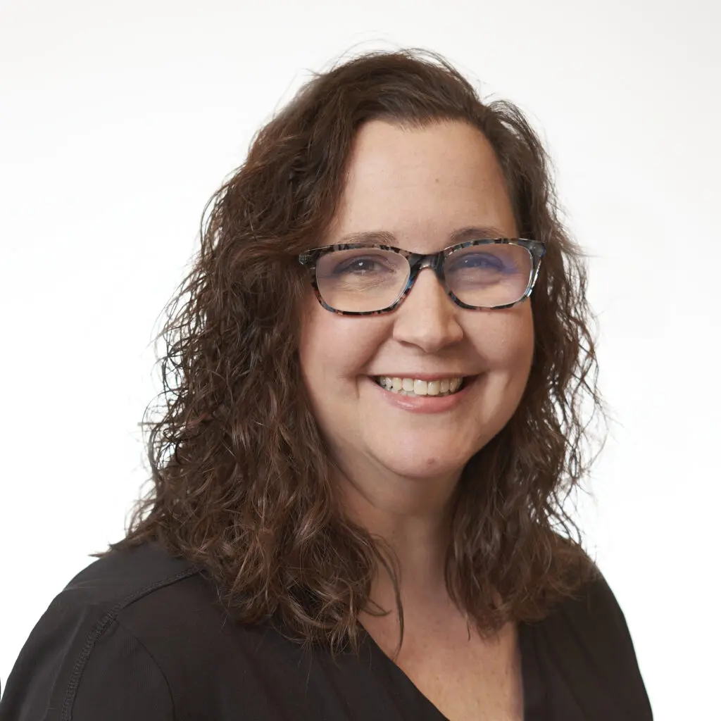 Courtney-Green-Office-Manager-1024x1024 Smiling woman with glasses and curly hair.