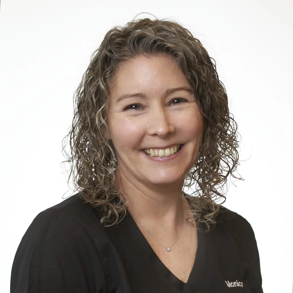 Monica-Hall-Dental-Assistant-1024x1024 Smiling person with curly hair, white background.