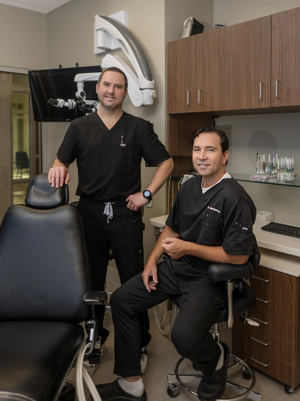 qt=q_98 Two men in black shirts and one is sitting on a dentist 's chair